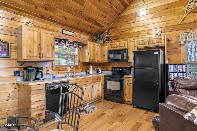 kitchen featuring light countertops, wood walls, a sink, and black appliances