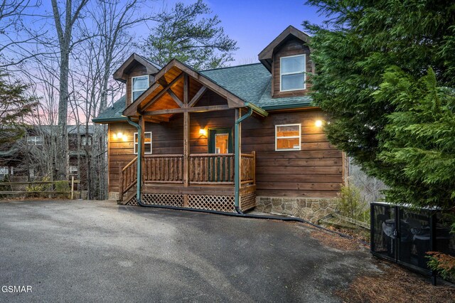 chalet / cabin featuring a porch and roof with shingles