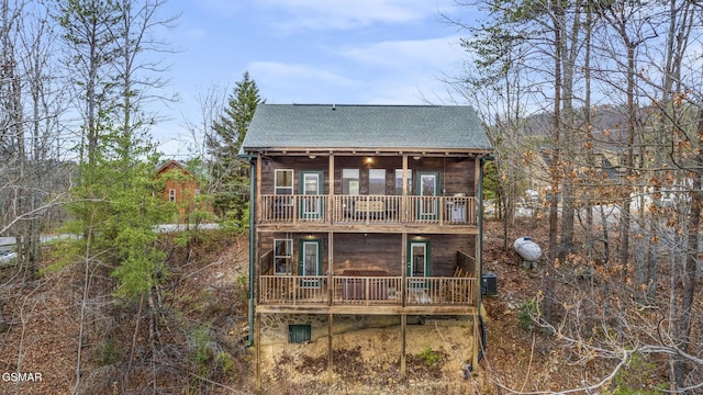 back of house featuring central AC unit, a wooden deck, and roof with shingles