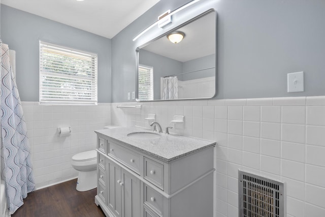 bathroom with vanity, heating unit, wood-type flooring, tile walls, and toilet