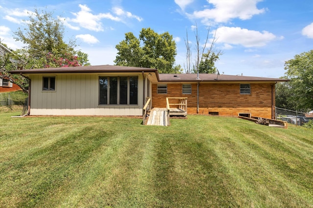 back of property featuring a lawn and a wooden deck