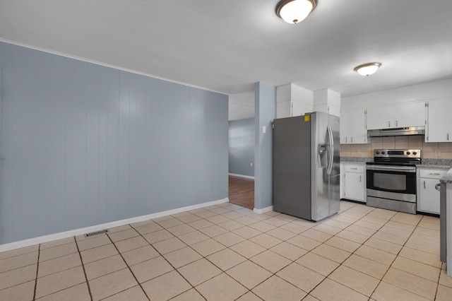 kitchen with appliances with stainless steel finishes, light tile patterned floors, white cabinetry, and ornamental molding