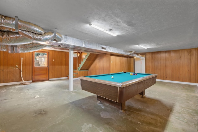 recreation room with wood walls, a textured ceiling, pool table, and concrete floors