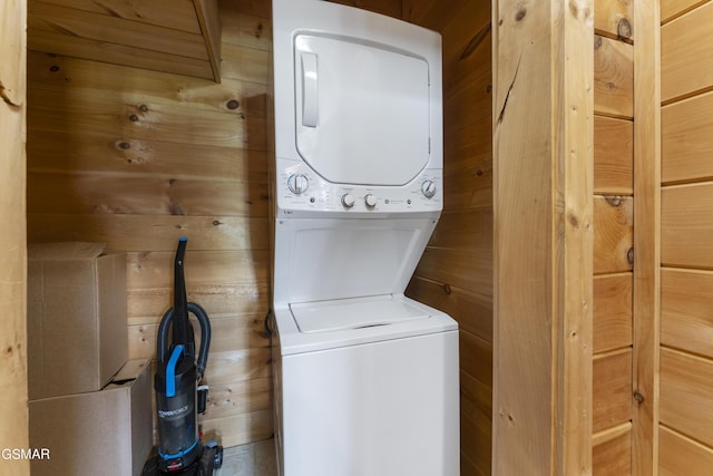 laundry room featuring wood walls and stacked washing maching and dryer