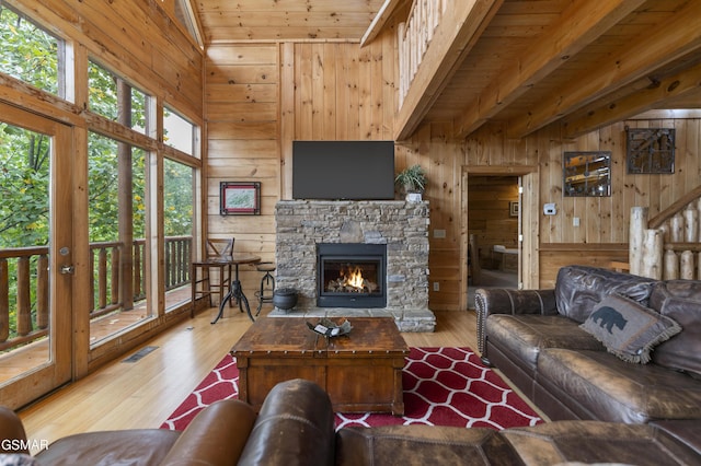 living room featuring hardwood / wood-style flooring, wood walls, a stone fireplace, and wood ceiling