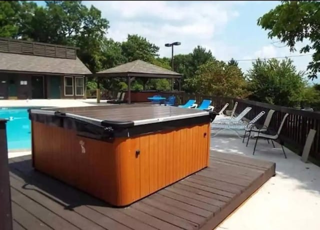 wooden terrace featuring a gazebo and a swimming pool with hot tub