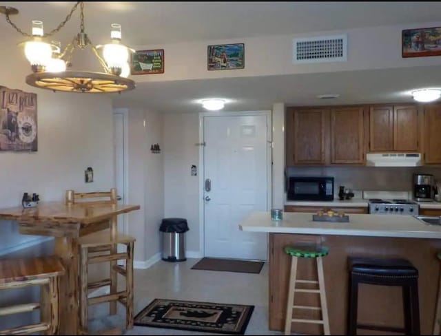 kitchen with white range with gas cooktop, a breakfast bar, hanging light fixtures, and an inviting chandelier