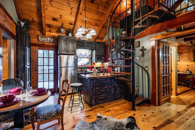 kitchen with beamed ceiling, wooden walls, wood ceiling, appliances with stainless steel finishes, and light wood finished floors
