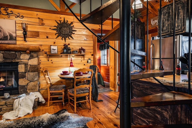 dining area with a fireplace, wooden walls, and hardwood / wood-style flooring