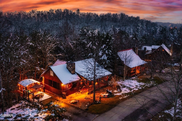 aerial view at dusk featuring a forest view