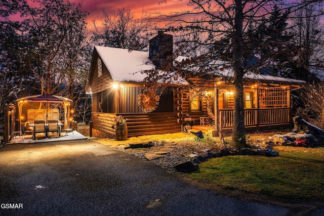 chalet / cabin with a chimney, a sunroom, and log siding