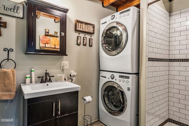 clothes washing area with a sink, cabinet space, and stacked washer / drying machine