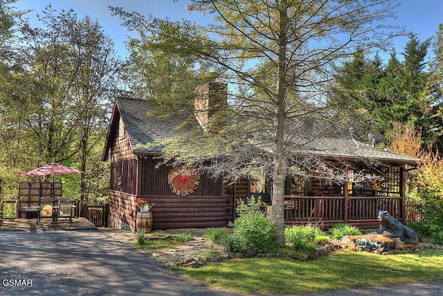 view of front of house featuring a chimney, a shingled roof, and log exterior