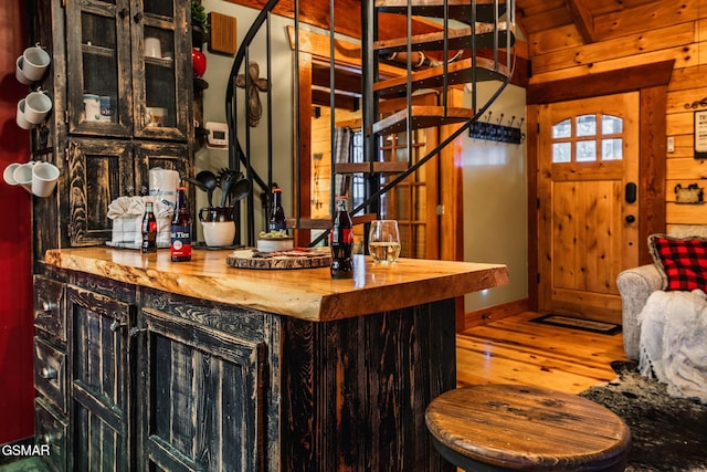 bar with wooden walls, stairway, and hardwood / wood-style floors