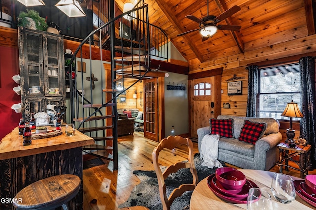 living room with stairway, wooden walls, a ceiling fan, hardwood / wood-style floors, and wood ceiling