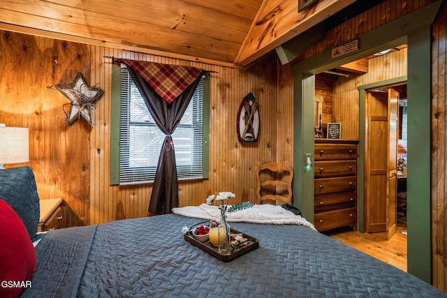 bedroom with wood walls, wood finished floors, and vaulted ceiling