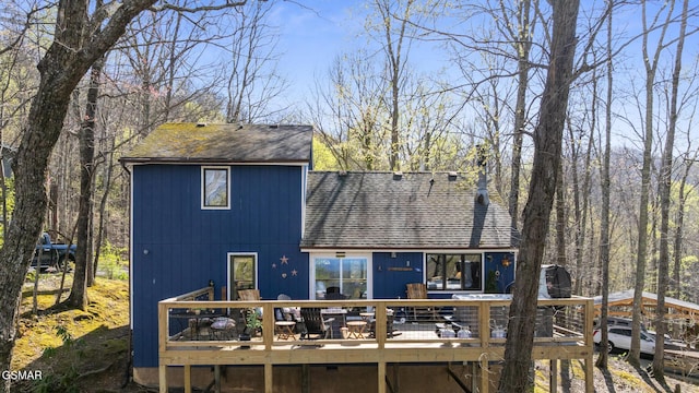 back of property featuring roof with shingles and a deck