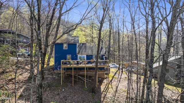 back of property featuring a wooden deck and roof with shingles