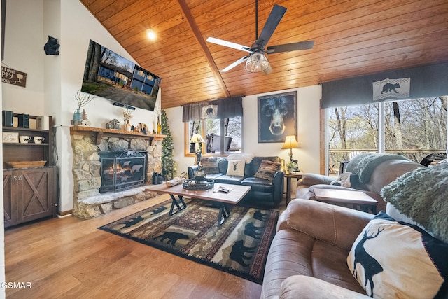 living area with lofted ceiling, a stone fireplace, wood finished floors, a ceiling fan, and wood ceiling