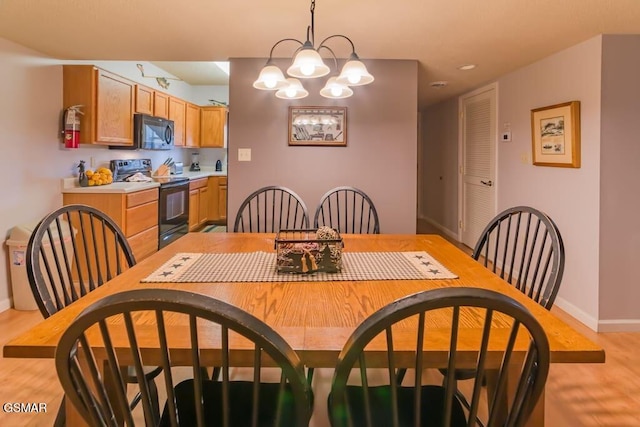 dining area with an inviting chandelier, baseboards, and light wood-style floors