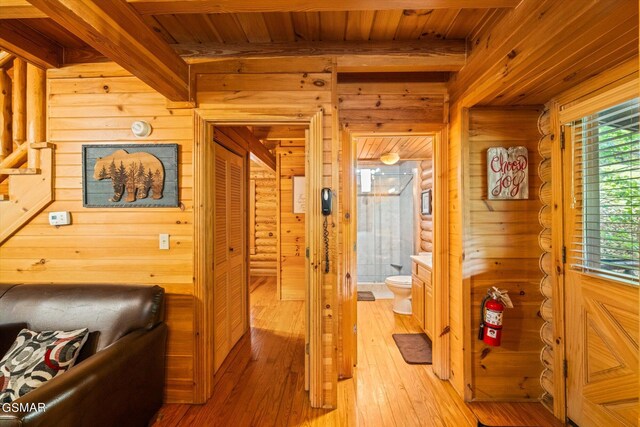 hallway featuring beam ceiling, wood walls, wooden ceiling, and light hardwood / wood-style floors