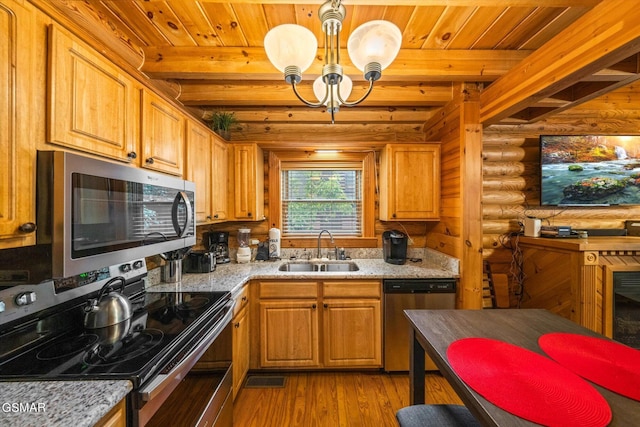 kitchen featuring beam ceiling, rustic walls, sink, appliances with stainless steel finishes, and hardwood / wood-style flooring