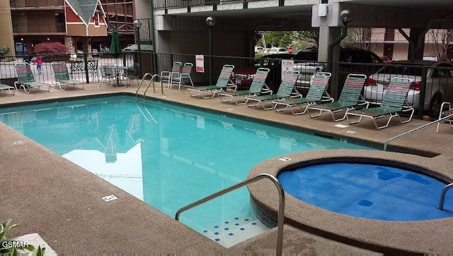 community pool with fence and a community hot tub