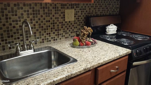 kitchen featuring light countertops, a sink, electric range, and decorative backsplash