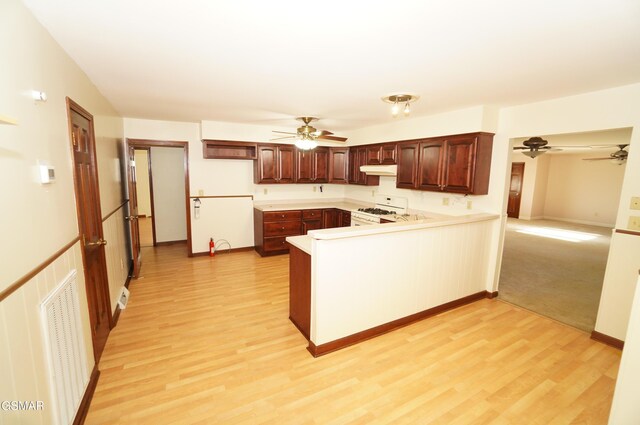 kitchen with white range with gas cooktop, kitchen peninsula, and light hardwood / wood-style flooring