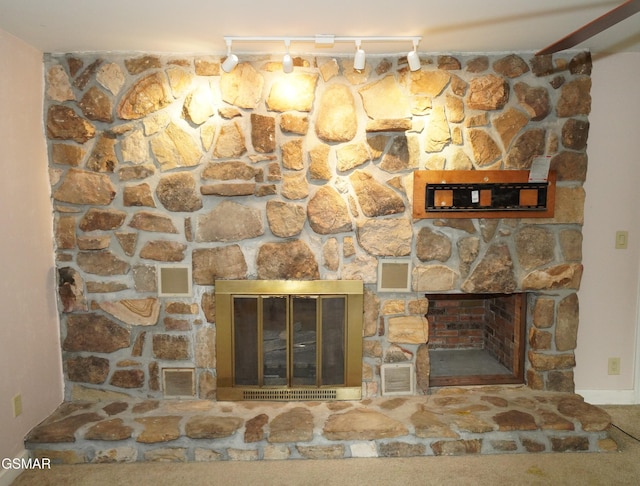 details featuring carpet flooring, a stone fireplace, and rail lighting