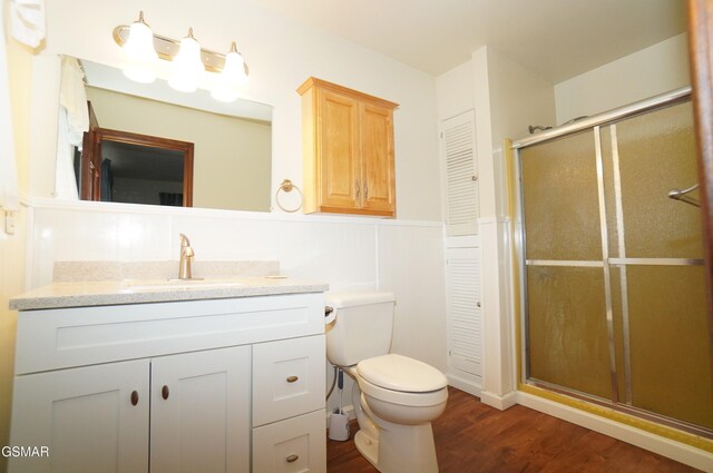 bathroom featuring hardwood / wood-style floors, vanity, an enclosed shower, and toilet