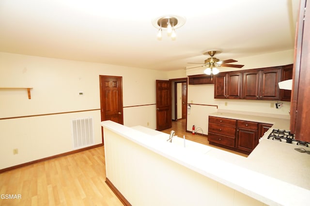 kitchen with ceiling fan, light wood-type flooring, and kitchen peninsula