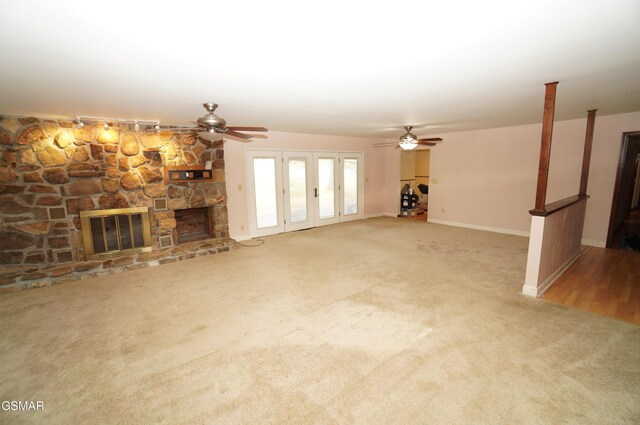 unfurnished living room with carpet, ceiling fan, and a stone fireplace