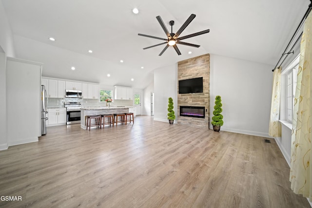 412 Apple Valley Rd, Sevierville, TN 37862 - unfurnished living room with vaulted ceiling, ceiling fan, recessed lighting, light wood-type flooring, and a fireplace