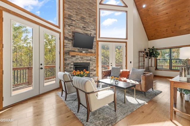 living room featuring french doors, high vaulted ceiling, a stone fireplace, and wood ceiling