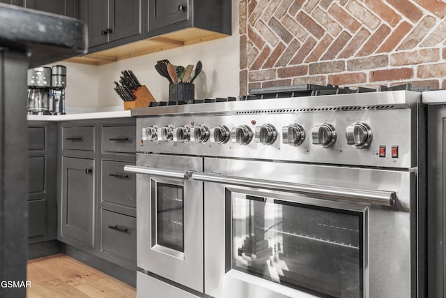 room details with gray cabinets, light hardwood / wood-style floors, and range with two ovens