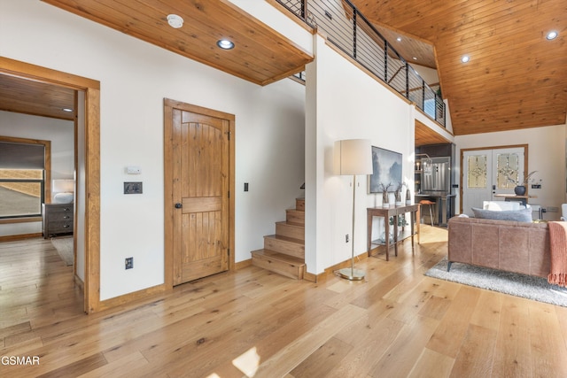 entrance foyer with a towering ceiling, light hardwood / wood-style flooring, wood ceiling, and french doors