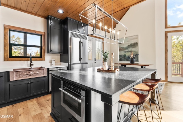 kitchen with a center island, wooden ceiling, hanging light fixtures, appliances with stainless steel finishes, and a kitchen bar