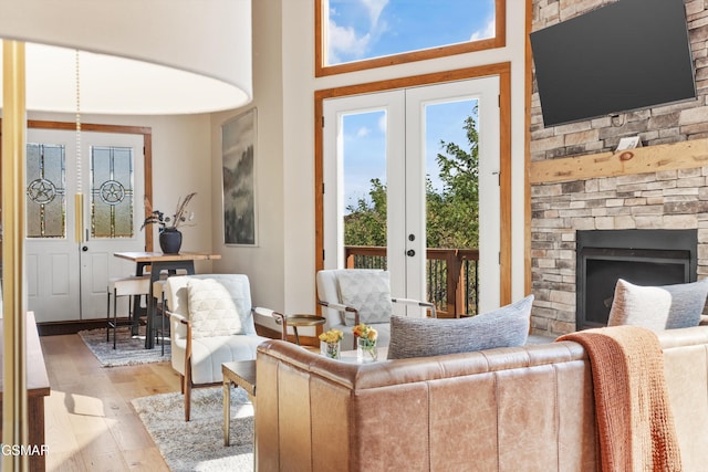 living room featuring hardwood / wood-style flooring, a stone fireplace, and french doors