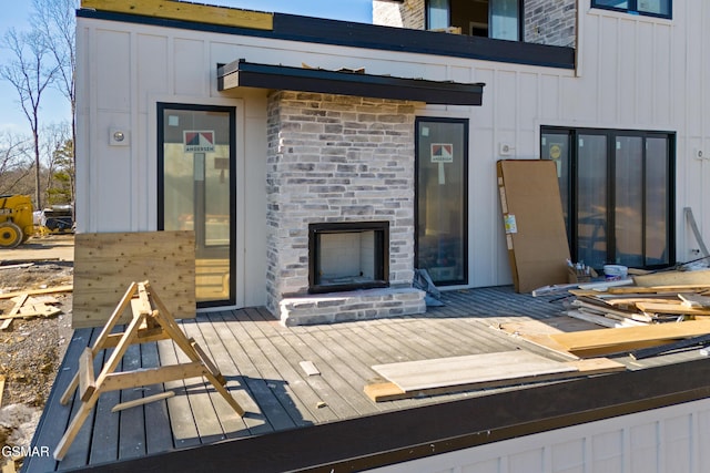 view of exterior entry with a wooden deck and an outdoor fireplace