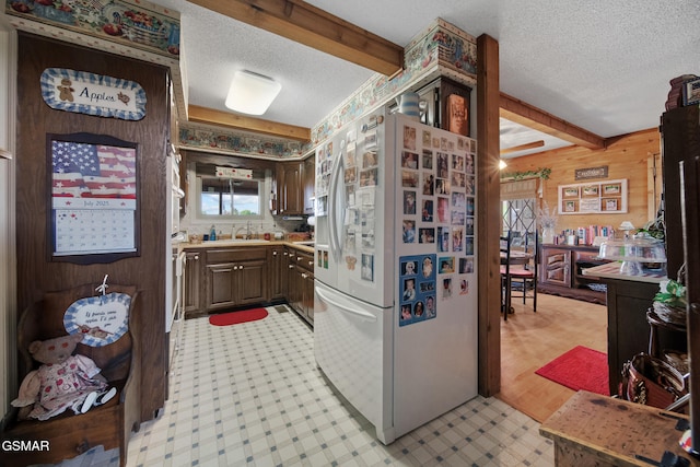 1505 Canterbury Ln, Sevierville, TN 37862 - kitchen featuring freestanding refrigerator, a textured ceiling, light countertops, wooden walls, and beamed ceiling