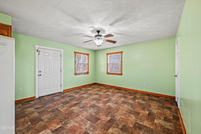 empty room with visible vents, baseboards, stone finish floor, a textured ceiling, and a ceiling fan