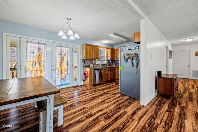 kitchen with visible vents, dark wood-style floors, a textured ceiling, brown cabinets, and stainless steel appliances