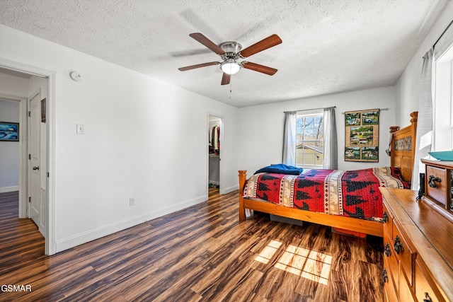 bedroom featuring baseboards, a textured ceiling, and wood finished floors