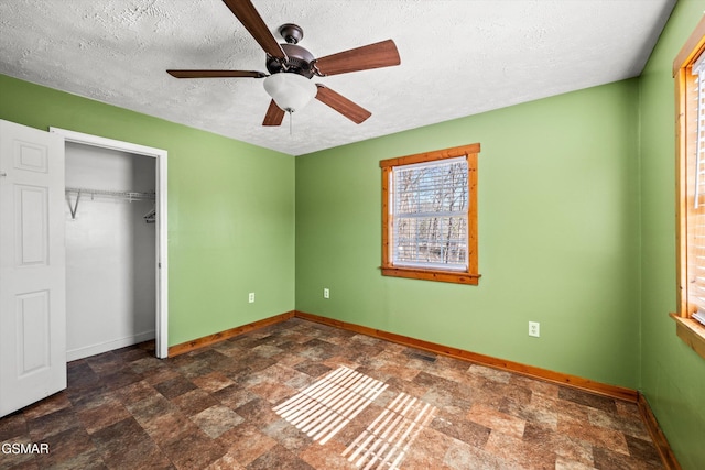 unfurnished bedroom with a textured ceiling, baseboards, stone finish flooring, visible vents, and a closet