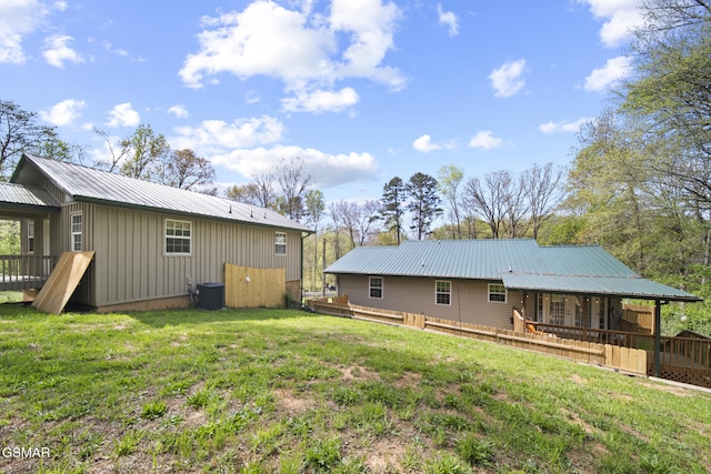 back of property featuring board and batten siding, a yard, cooling unit, and metal roof