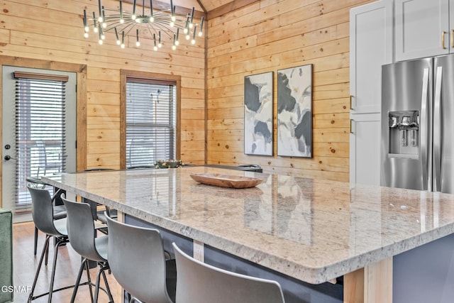 kitchen featuring stainless steel fridge, light stone counters, and a kitchen breakfast bar