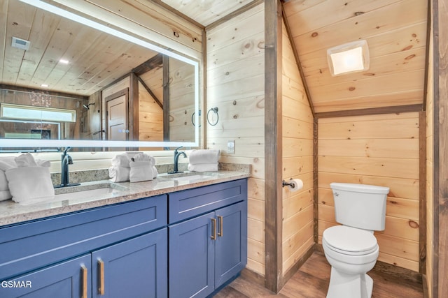 bathroom featuring wooden ceiling, a sink, wooden walls, and wood finished floors