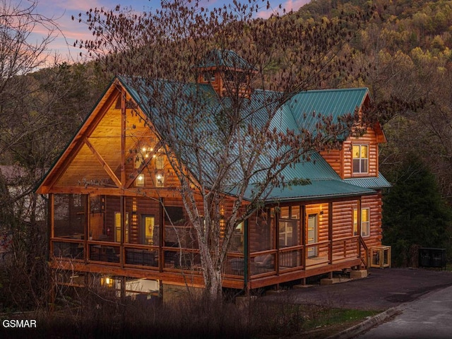 rear view of property featuring a sunroom and metal roof