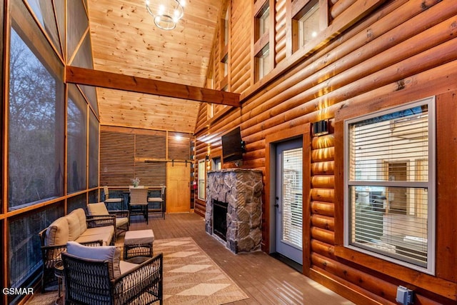 sunroom / solarium featuring vaulted ceiling, a stone fireplace, and wood ceiling